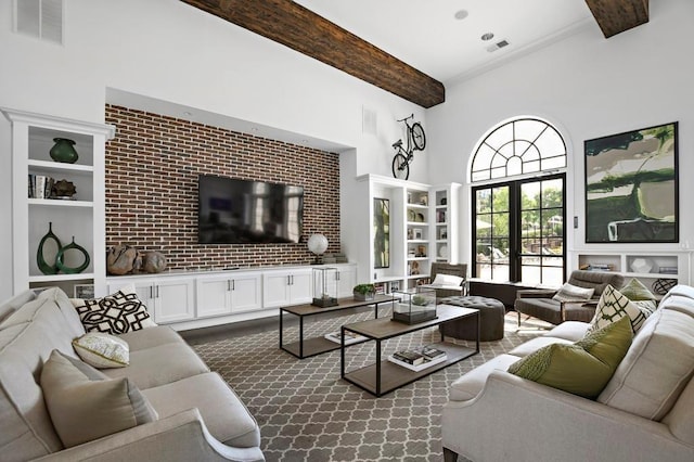 living room with french doors, brick wall, beam ceiling, and a high ceiling