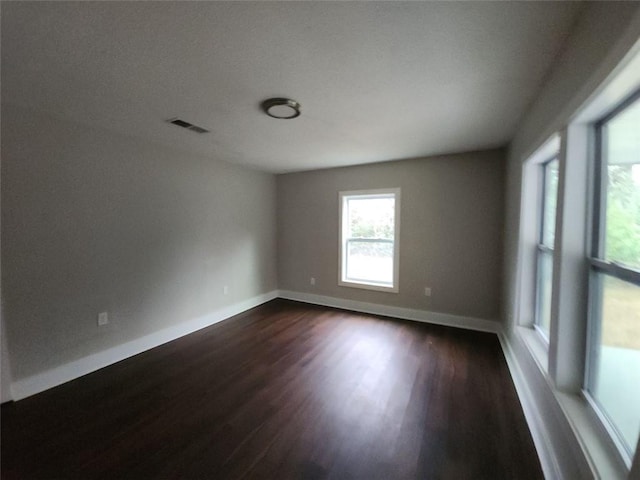 unfurnished room with dark wood-type flooring