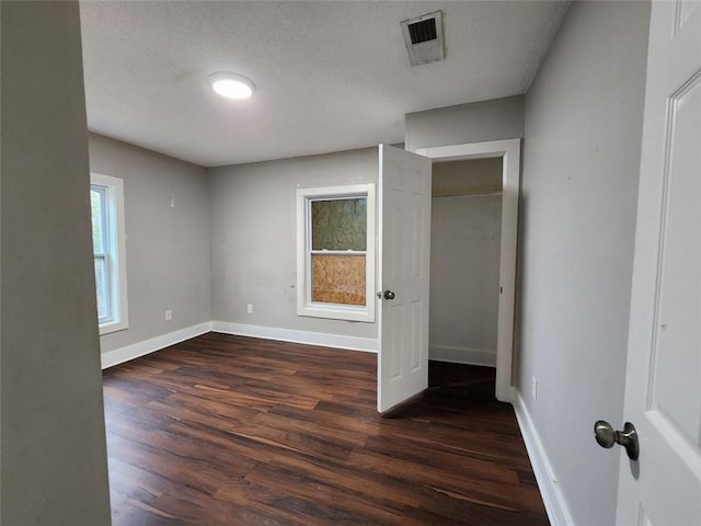 unfurnished bedroom featuring a textured ceiling and dark hardwood / wood-style floors