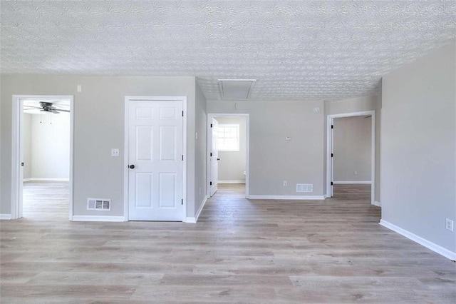 unfurnished room with ceiling fan, a textured ceiling, and light hardwood / wood-style flooring