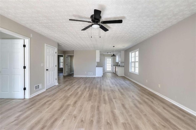 unfurnished living room featuring ceiling fan, light hardwood / wood-style floors, and a textured ceiling