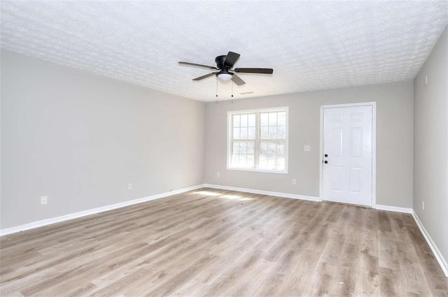 empty room with ceiling fan, a textured ceiling, and light wood-type flooring