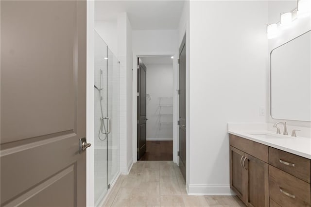 bathroom featuring a shower with shower door and vanity