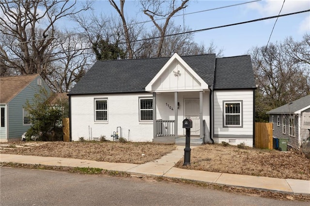 bungalow featuring covered porch, brick siding, crawl space, roof with shingles, and board and batten siding