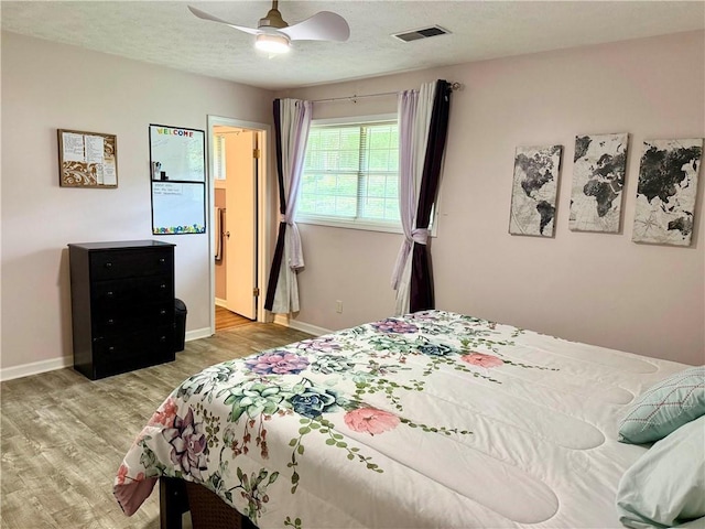 bedroom featuring wood finished floors, baseboards, a ceiling fan, and a textured ceiling
