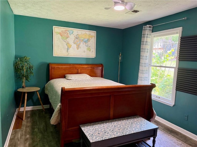 bedroom with wood finished floors, multiple windows, a textured ceiling, and baseboards