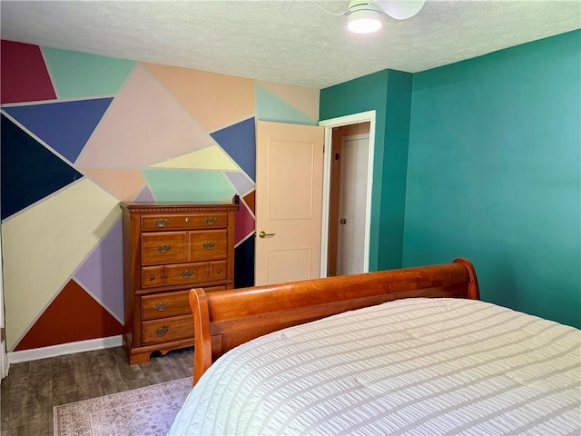 bedroom with wood finished floors, a textured ceiling, and baseboards