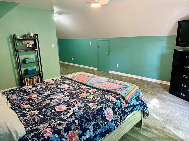bedroom featuring vaulted ceiling, baseboards, and wood finished floors