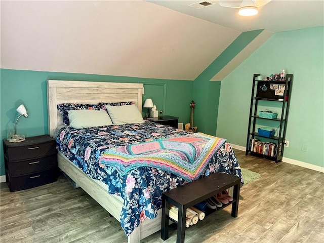 bedroom with wood finished floors, vaulted ceiling, and baseboards