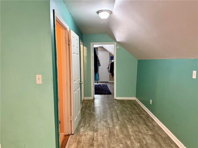 hallway with wood finished floors, lofted ceiling, and baseboards