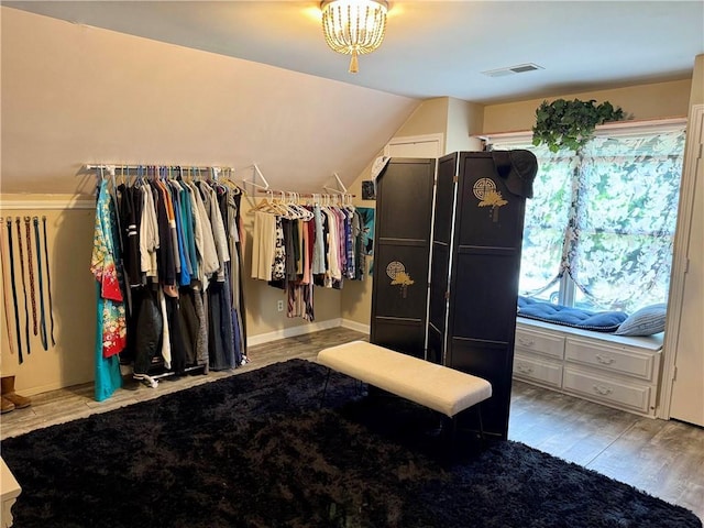 walk in closet featuring lofted ceiling, wood finished floors, and a chandelier