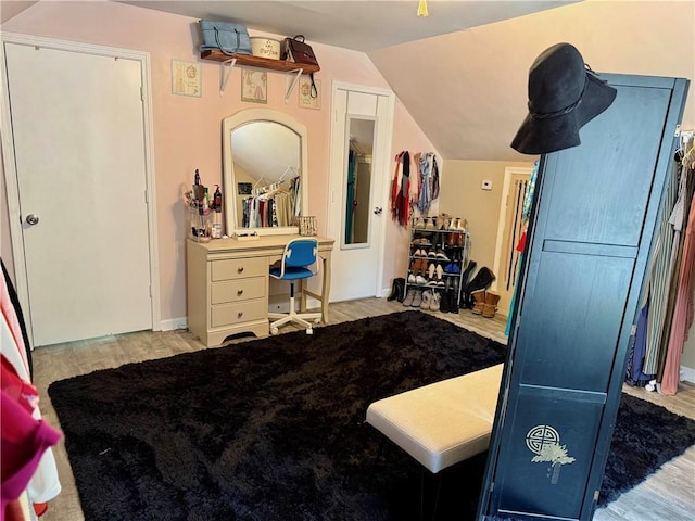 bedroom with wood finished floors and lofted ceiling