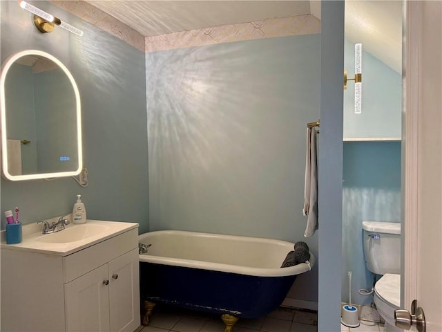 full bathroom with a freestanding tub, vanity, toilet, and tile patterned floors