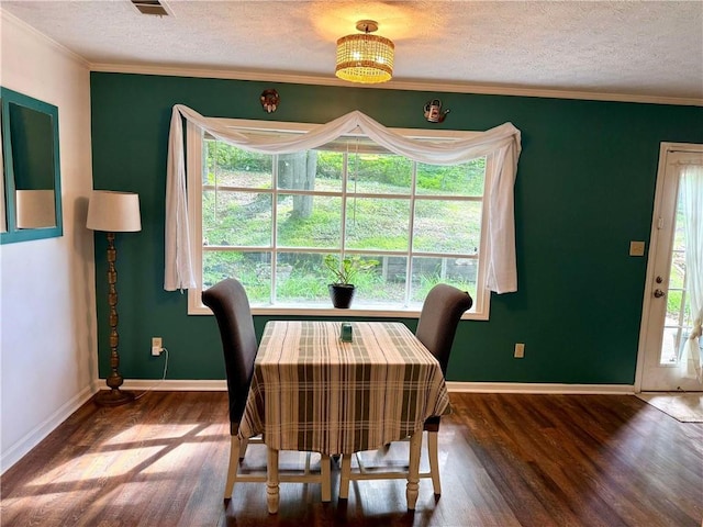 dining room featuring wood finished floors, a textured ceiling, plenty of natural light, baseboards, and crown molding