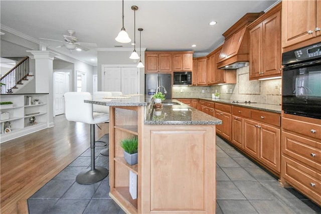 kitchen with premium range hood, a breakfast bar, decorative light fixtures, a center island with sink, and black appliances