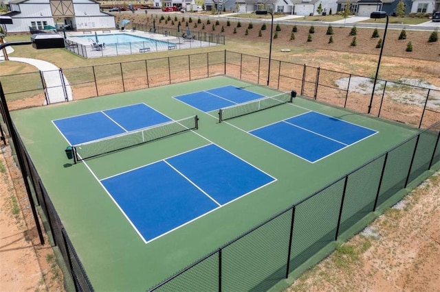 view of tennis court featuring a community pool