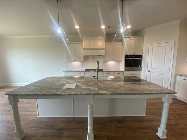 216 Montview Dr, Jefferson, GA 30549 - kitchen with oven, white cabinetry, crown molding, a large island with sink, and dark stone countertops