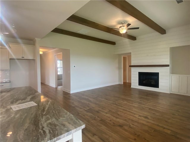 216 Montview Dr, Jefferson, GA 30549 - unfurnished living room featuring a ceiling fan, dark wood-style floors, beam ceiling, a large fireplace, and baseboards