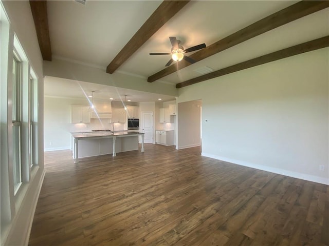 216 Montview Dr, Jefferson, GA 30549 - unfurnished living room with beam ceiling, dark wood-style flooring, a ceiling fan, and baseboards