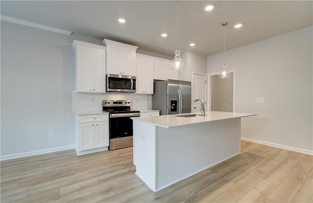 8147 Tiger Way, Riverdale, GA 30296 - kitchen featuring stainless steel appliances, a sink, a center island with sink, light countertops, and light wood finished floors