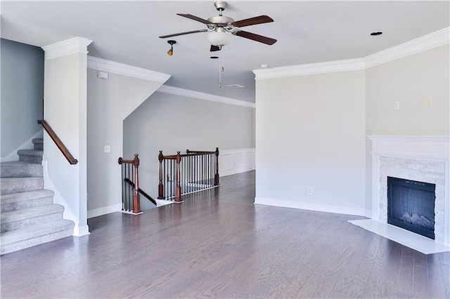 living room with dark wood-type flooring, ceiling fan, a fireplace, and crown molding