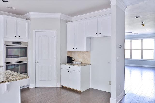 kitchen with crown molding, light stone countertops, double oven, and white cabinets