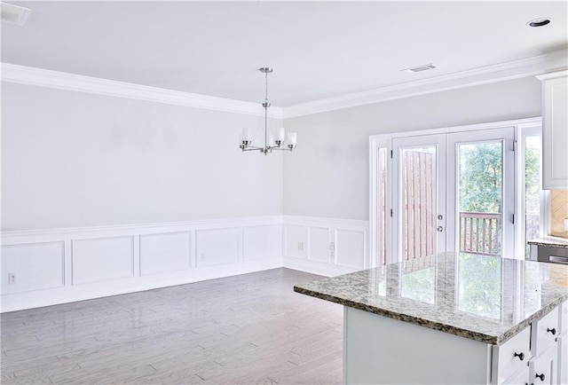 unfurnished dining area featuring crown molding, wood-type flooring, and a chandelier