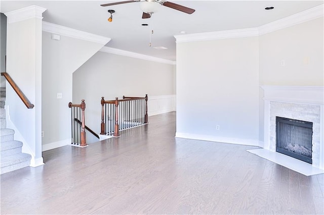 living room with hardwood / wood-style flooring, ornamental molding, ceiling fan, and a fireplace