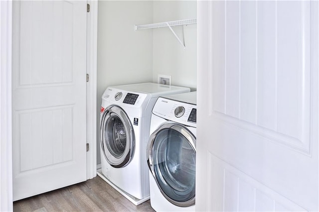 laundry room with wood-type flooring and washing machine and clothes dryer