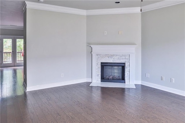 unfurnished living room with dark wood-type flooring, ornamental molding, a stone fireplace, and french doors