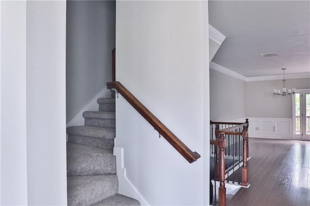 stairway featuring ornamental molding, wood-type flooring, and a chandelier