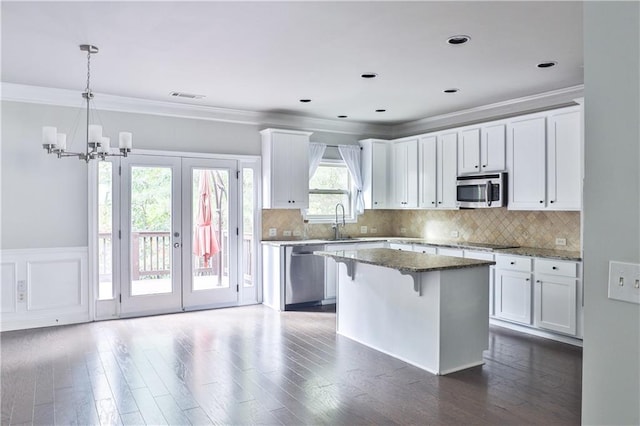 kitchen featuring white cabinetry, appliances with stainless steel finishes, a center island, and dark stone counters