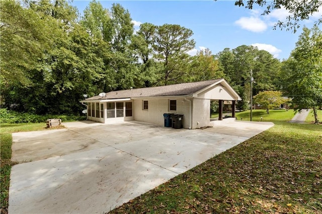 rear view of property with driveway, a yard, and a sunroom