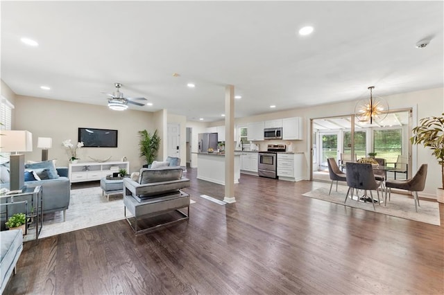 living room with recessed lighting, baseboards, dark wood finished floors, and ceiling fan with notable chandelier