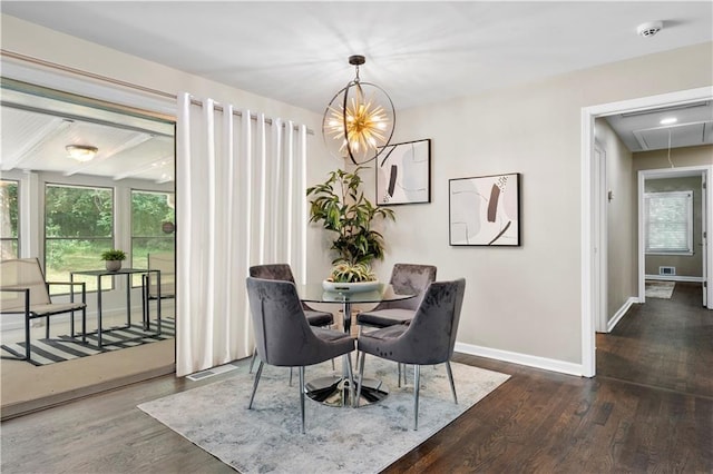 dining space with wood finished floors, visible vents, baseboards, attic access, and a chandelier