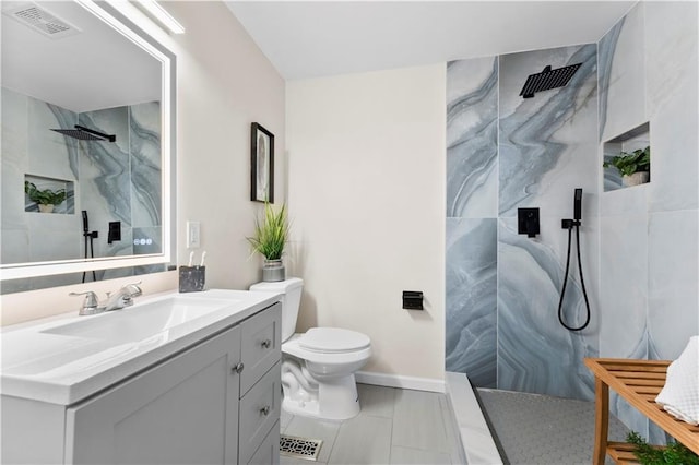 bathroom with vanity, baseboards, visible vents, walk in shower, and toilet