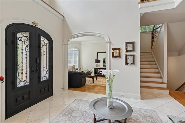 tiled foyer entrance with french doors, plenty of natural light, and ornamental molding