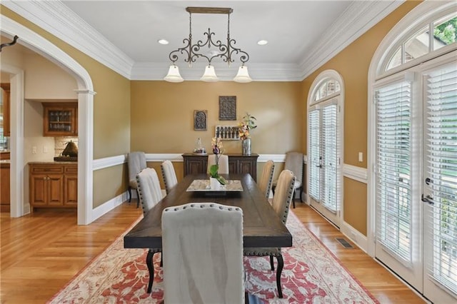 dining room with a healthy amount of sunlight, crown molding, and light hardwood / wood-style floors