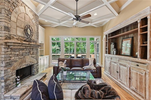 living room with light hardwood / wood-style floors, coffered ceiling, ceiling fan, a fireplace, and ornamental molding