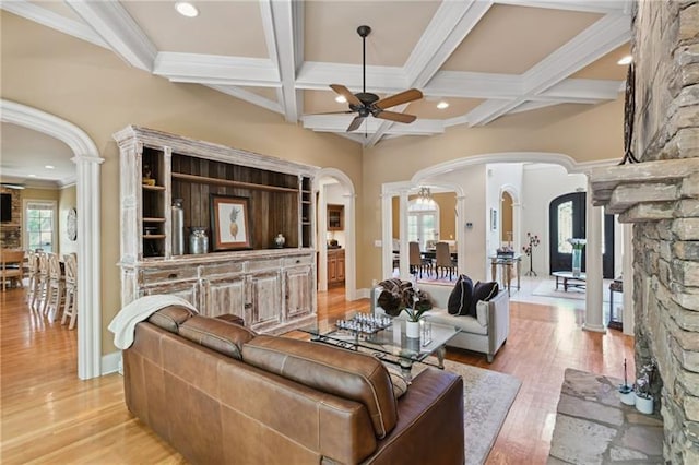 living room with beamed ceiling, light hardwood / wood-style floors, ornamental molding, ceiling fan, and decorative columns