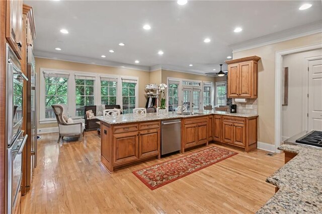 kitchen featuring kitchen peninsula, stainless steel appliances, backsplash, light stone countertops, and light hardwood / wood-style flooring