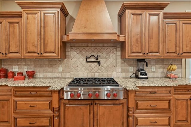 kitchen featuring stainless steel gas cooktop, custom exhaust hood, tasteful backsplash, and light stone counters