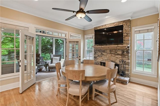 dining space with french doors, a fireplace, plenty of natural light, and light hardwood / wood-style floors