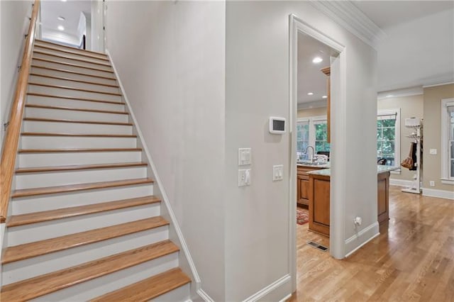 stairway featuring hardwood / wood-style flooring, sink, and ornamental molding