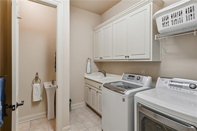 laundry room with cabinets, light tile patterned flooring, separate washer and dryer, and sink