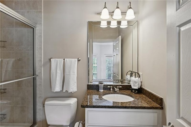 bathroom with toilet, a shower with shower door, and vanity