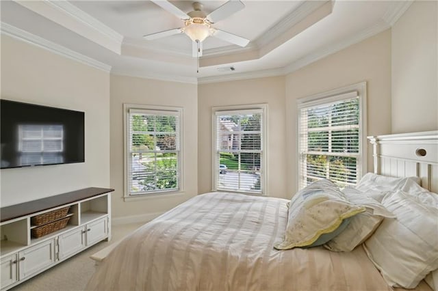 carpeted bedroom with ceiling fan, a tray ceiling, and ornamental molding