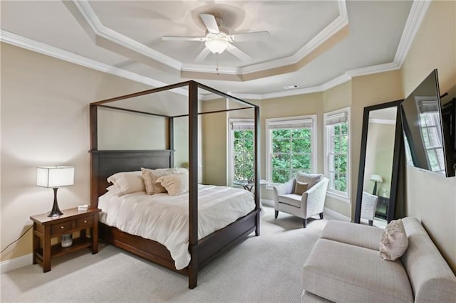 carpeted bedroom with ceiling fan, ornamental molding, and a raised ceiling