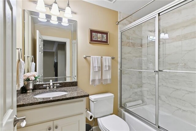 full bathroom with bath / shower combo with glass door, toilet, and vanity