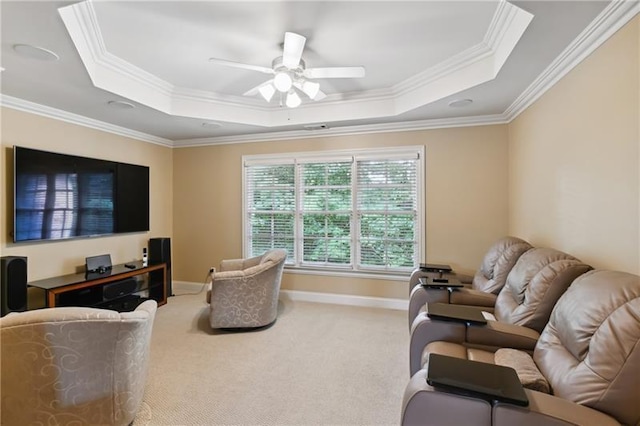 living room featuring ceiling fan, a tray ceiling, ornamental molding, and carpet flooring